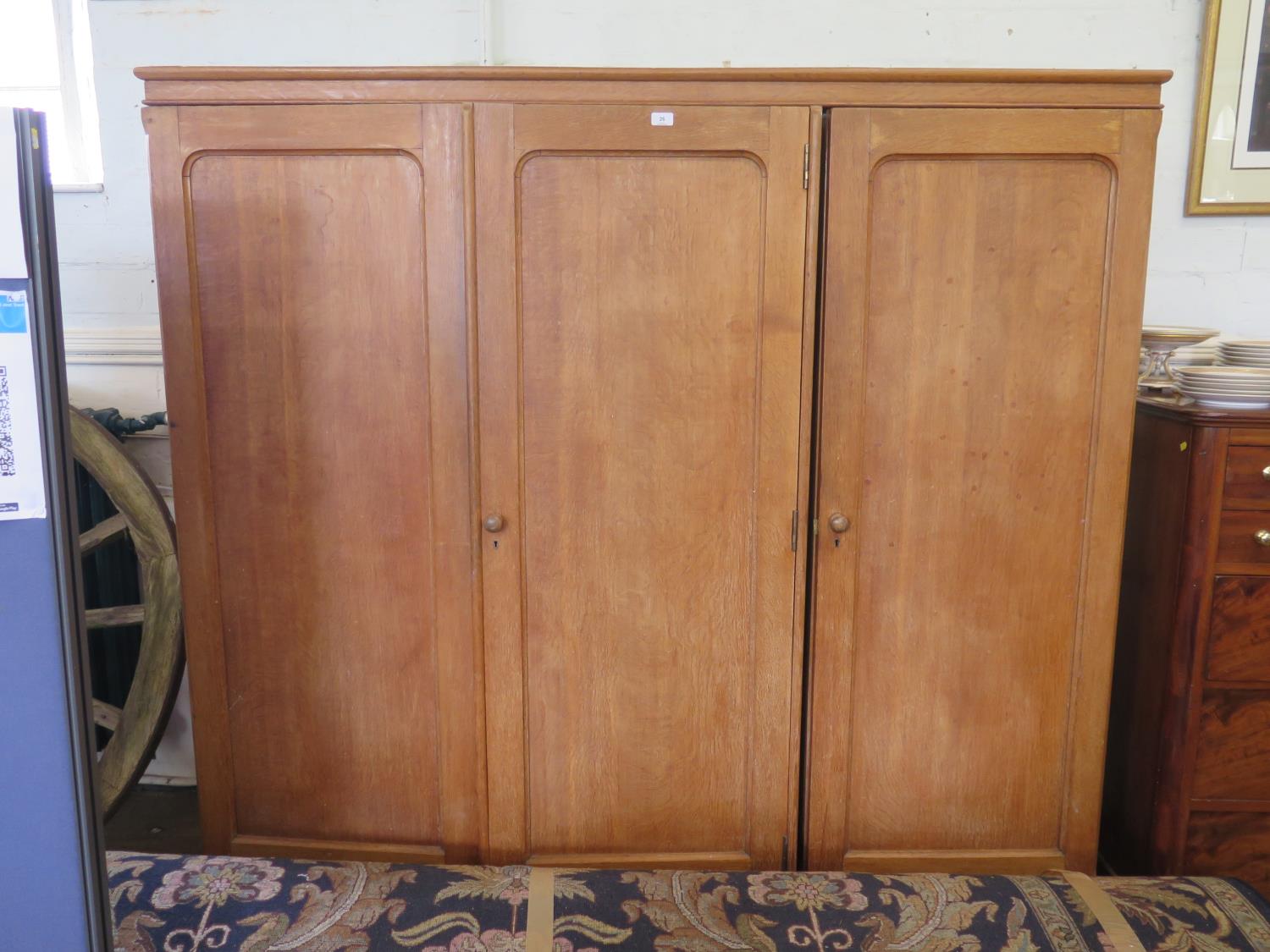 An oak three door linen press and wardrobe, the twin doors enclosing drawers, the third door
