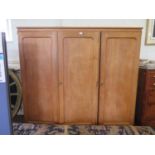 An oak three door linen press and wardrobe, the twin doors enclosing drawers, the third door