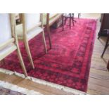 An Afghan style carpet, the all over red design with medallions of stylised creatures and pendant