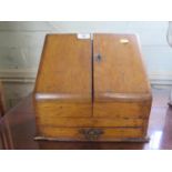 A late Victorian oak stationery cabinet, with sloping twin doors enclosing compartments over a