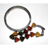 A bracelet of eleven polished amber pieces together with a white metal and enamel bangle