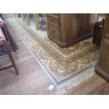 A French style carpet, the pink and gold floral scroll design on a cream field and similar border,