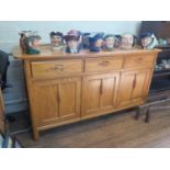 A light elm Ercol sideboard, with three frieze drawers over three panelled cupboard doors, on