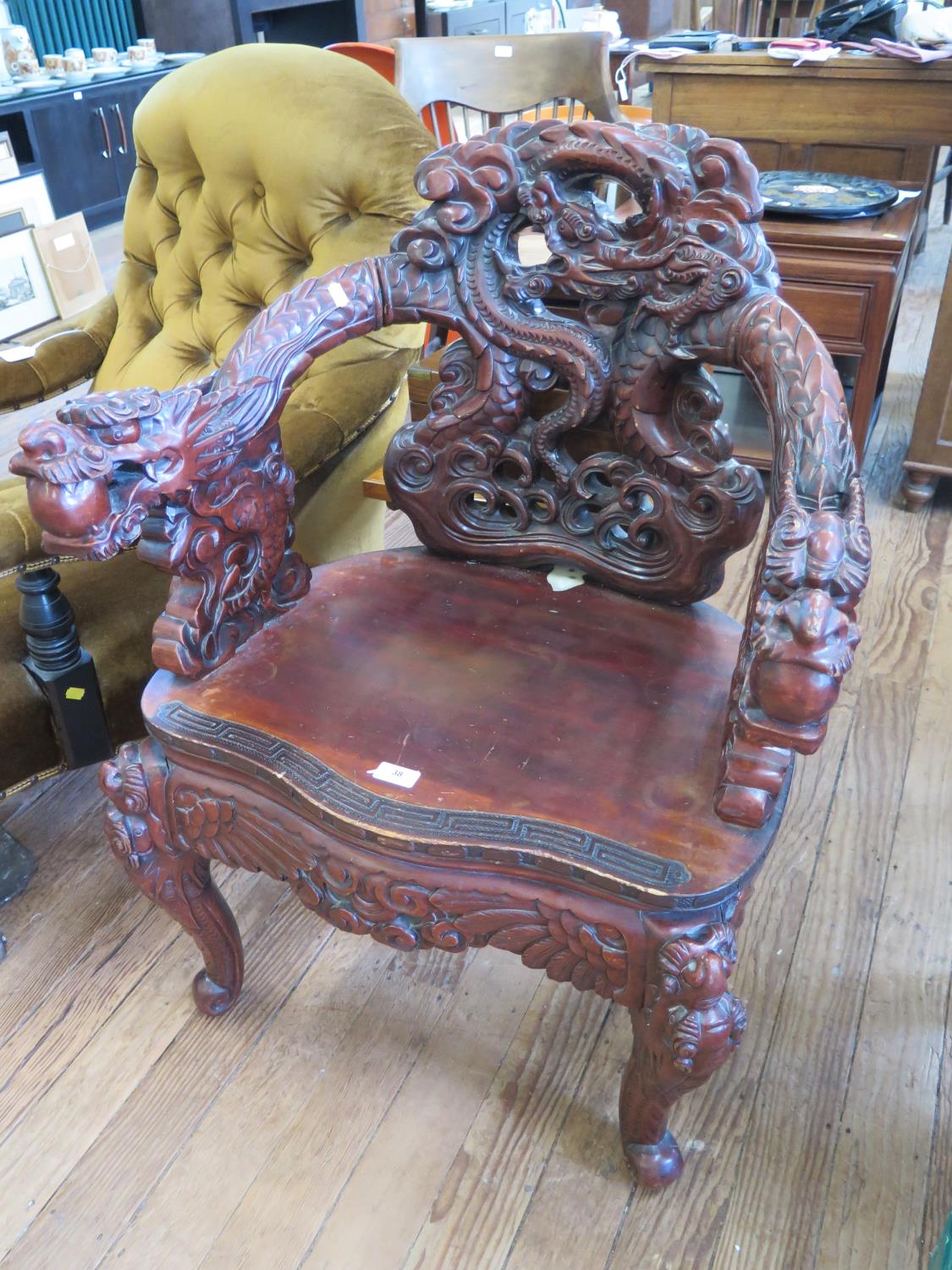 A profusely carved Chinese armchair, the back and arms carved with dragons over a winged seat