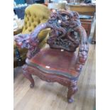 A profusely carved Chinese armchair, the back and arms carved with dragons over a winged seat