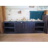 A Rebecca Scott ebony finish low side cabinet, the twin cupboard doors flanked by open shelves on