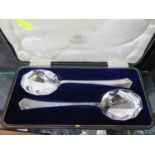 A pair of silver dessert serving spoons in presentation case