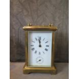 A brass carriage clock, of conventional form, the enamel dial with alarm subsidiary dial, the two