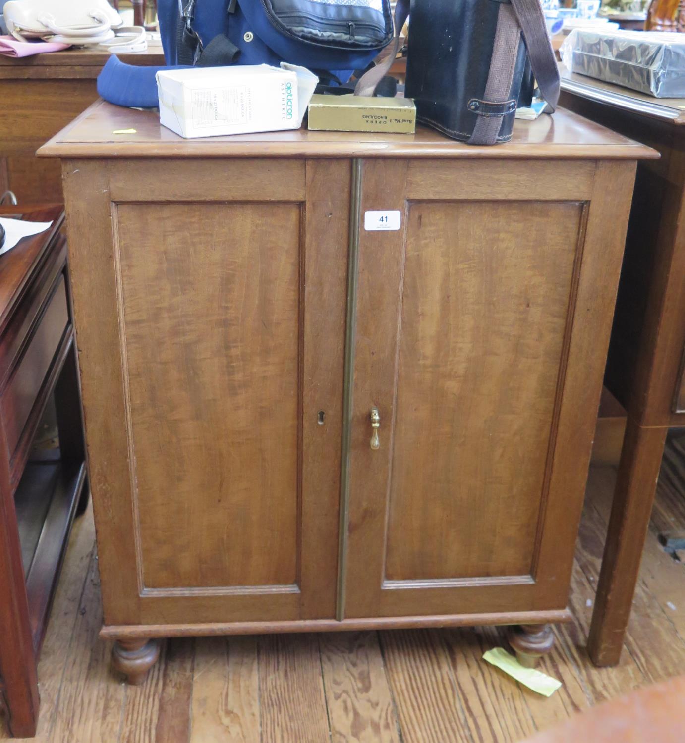 A mahogany cabinet with twin panelled doors enclosing a shelf, on turned legs, 65 cm wide