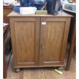 A mahogany cabinet with twin panelled doors enclosing a shelf, on turned legs, 65 cm wide