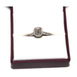 A cushion cut diamond cluster ring, set in platinum with diamonds on the shoulders, the central