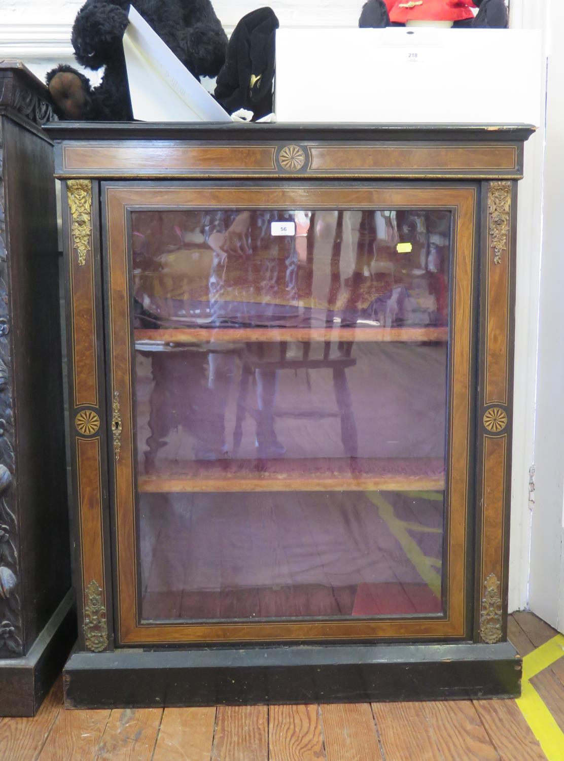 A late Victorian ebonised and walnut side cabinet, the patera inlaid frieze over a glazed door