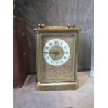 An Edwardian brass carriage timepiece clock, the floral scroll decorated dial with enamelled chapter