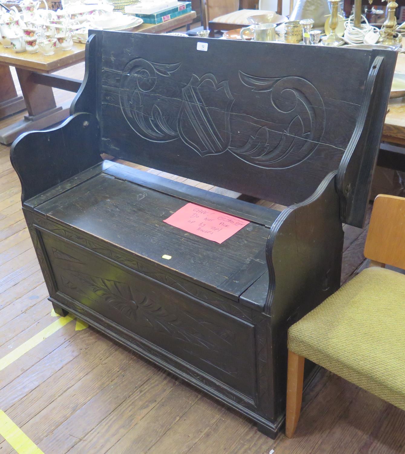 A carved oak monks bench, the hinged top over a lidded seat with lozenge carved front, 106 cm