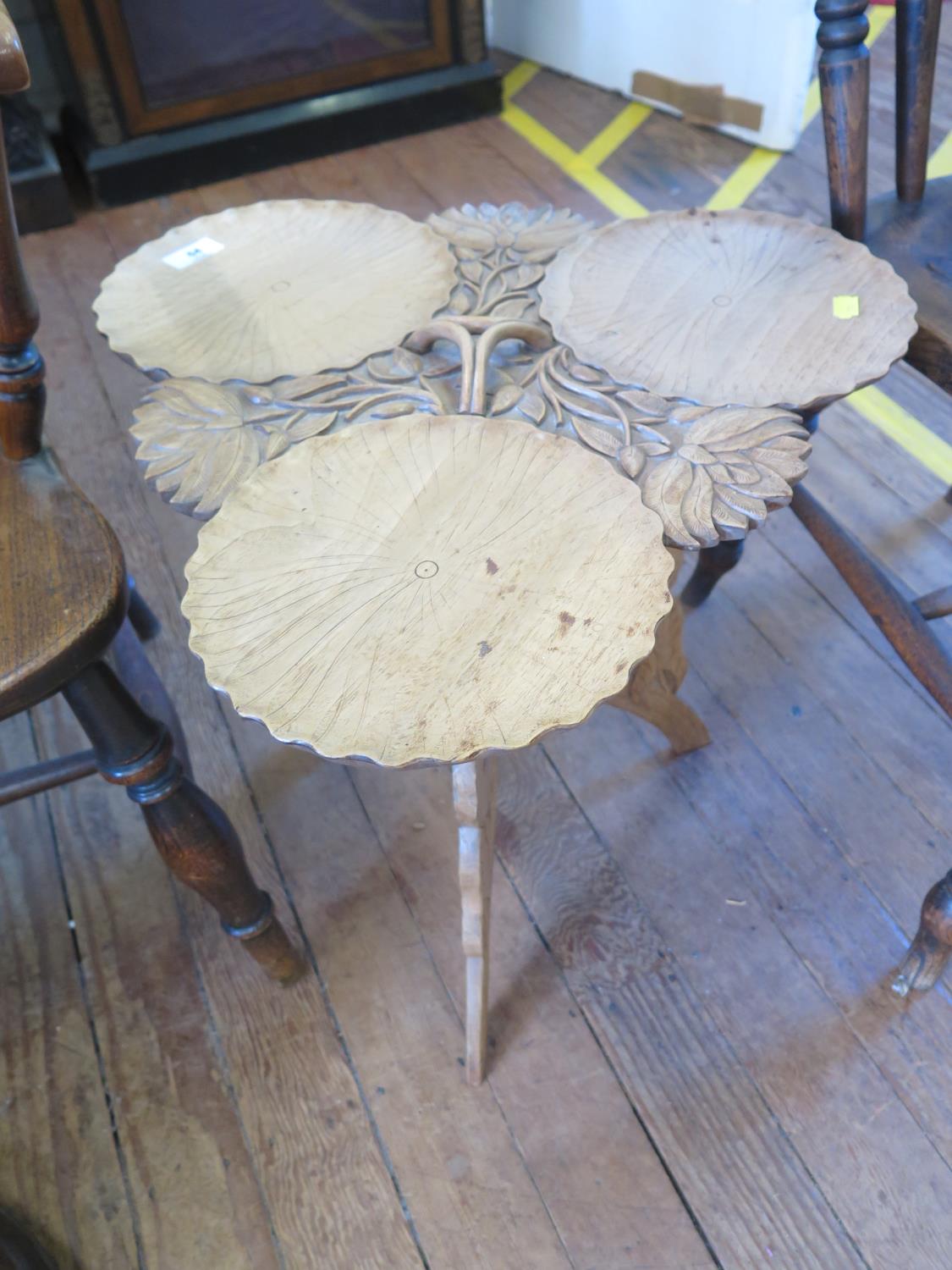 A carved wood Indian table, the top in the form of three lily pads, on a folding carved tripod base,