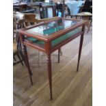 A satinwood crossbanded mahogany bijouterie table, the hinged glazed top enclosing a baize lined