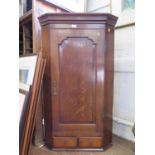 A George III oak hanging corner cabinet, the panelled cupboard door enclosing shaped shelves over