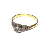 A single stone diamond ring, with foliate design shoulders set in gold coloured metal