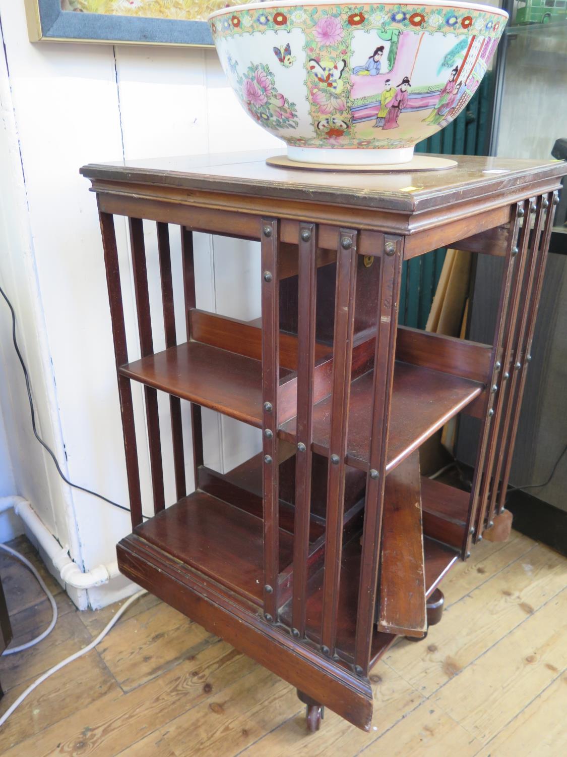 A mahogany revolving bookcase, with slat sides on a cross frame base, 50 cm square, 85 cm high