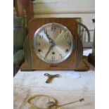 An inlaid walnut Art Deco style mantel clock, with silvered dial and three train movement striking