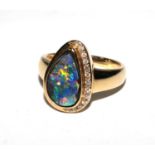 A yellow dress ring with a free form pear shaped 'black' boulder opal and round brilliant cut