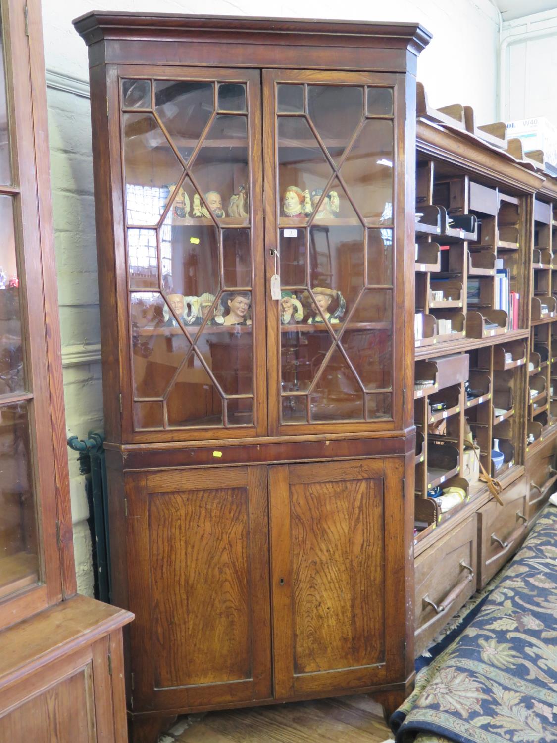 A George III elm corner cabinet, the moulded cornice over a pair of glazed doors enclosing shaped