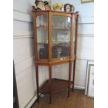 An Edwardian inlaid mahogany corner display cabinet, the raised back over a glazed door, on long