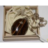 A large oval tigers eye pendant mounted on silver hallmarked London 1975 with 63 cm chain