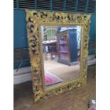 A Baroque style gilt pine wall mirror, the bevelled rectangular plate within an open foliate