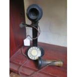 A blacked metal stick telephone, marked M23 235, with rotating dial