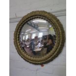A giltwood convex wall mirror, the circular plate within a cabochon and foliate carved frame, 55
