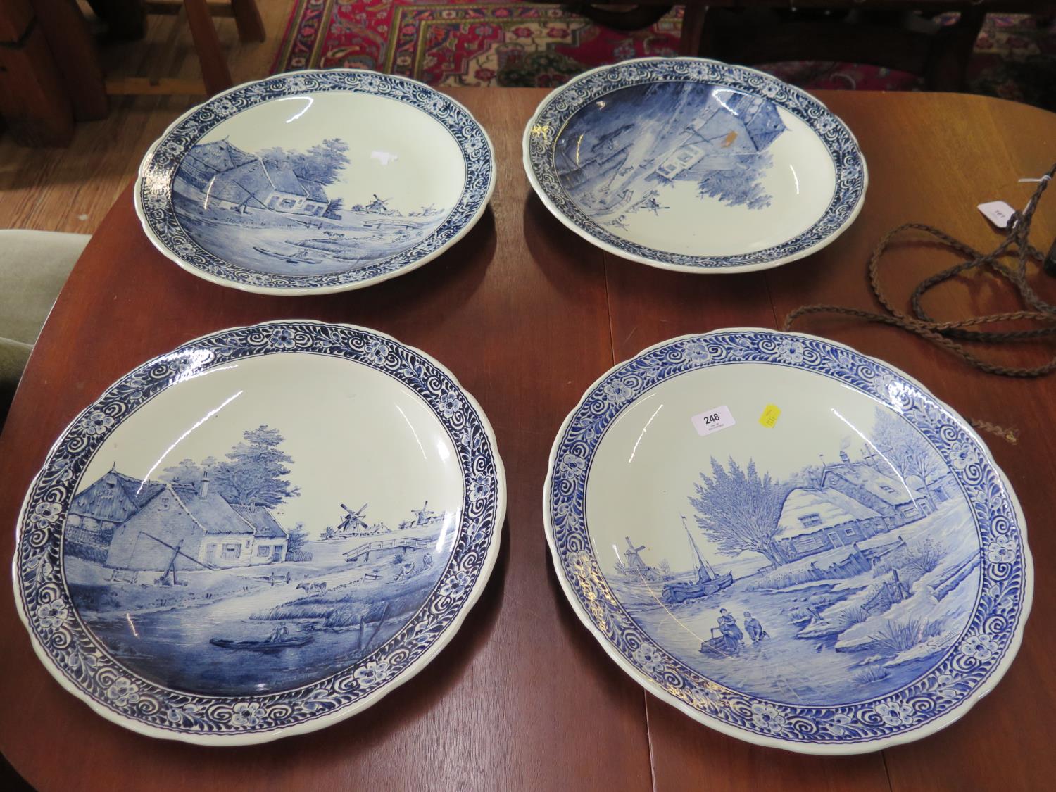 Four Boch Delft chargers, with Dutch landscapes after J. Sonneville, three depicting the same scene,