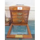 An Edwardian walnut jewellery cabinet, the hinged lid enclosing a silk lined interior, over a glazed