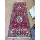A Persian thick pile runner, with ivory and brown medallions on a red ground, 195 x 70 cm