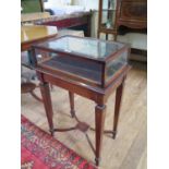 A mahogany bijouterie table, the hinged glazed top on inlaid square tapering legs joined by cross