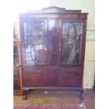 A 1930s mahogany display cabinet, the raised back over a pair of glazed doors and panelled centre