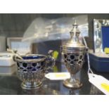 A silver salt in the form of a double handled cup with pierced decoration, blue liner and salt spoon