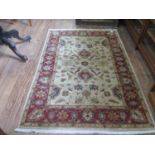 A Zeigler style rug, with beige field and red border, filled with flowerheads and foliage, 204 x 137