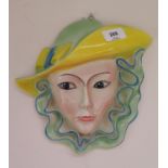 A Shorter and Son Pottery wall mask of a young lady wearing bright green and yellow hat