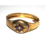 A gold colour metal bangle, decorated with blue enamel and a pearl set star