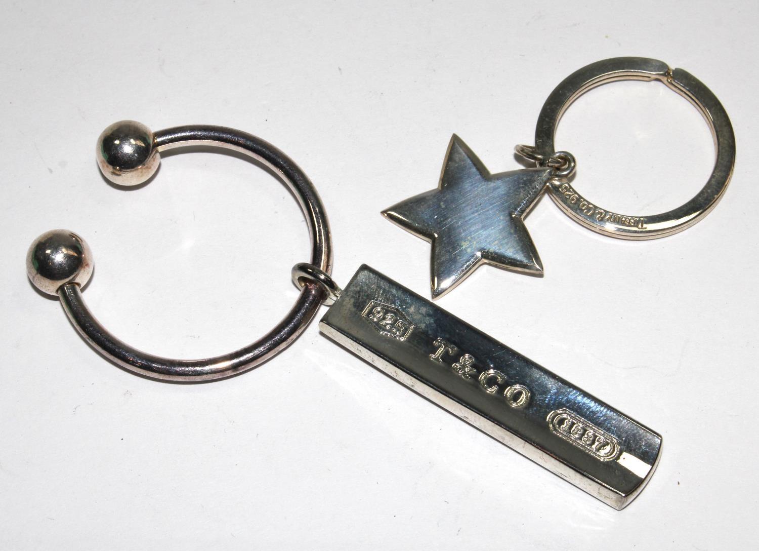 A Tiffany & Co ball and bar silver key ring, and a similar silver star key ring, both marked 925, in