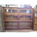 A 1930s oak bookcase, carved with owls, the two banks of three shelves with glazed fall fronts,