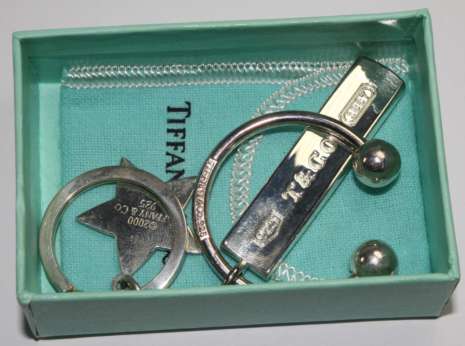 A Tiffany & Co ball and bar silver key ring, and a similar silver star key ring, both marked 925, in - Image 2 of 2