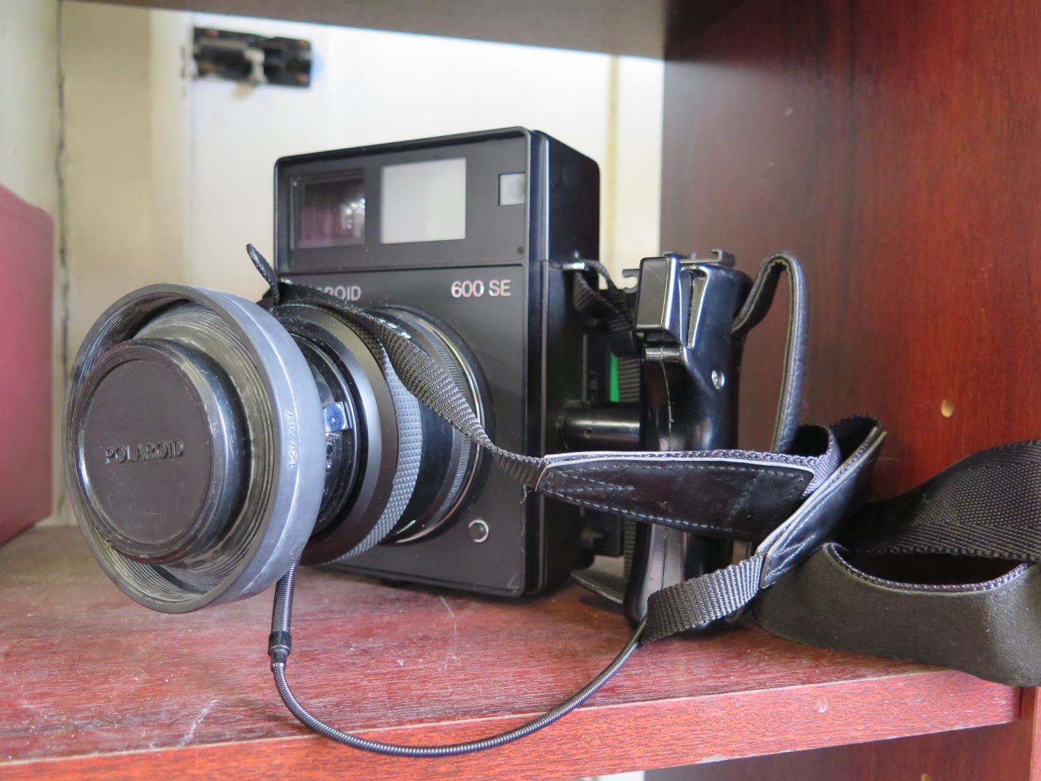 A Polaroid 600 SE camera, with Mamiya 127mm lens, and a Sachtler DV 4 video camera tripod (with