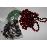 A green bead necklace, a red bead necklace and a collection of amber type beads