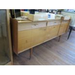 A 1960s teak sideboard, with three concave moulded drawers over a central cupboard with fall front