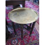 A Middle Eastern brass circular tray, 59 cm diameter, on a turned folding stand