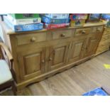 A pine dresser base, with four short drawers over two pairs of panelled doors on a shaped plinth