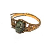 A gold coloured ring set with a small scarab (damaged)