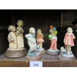 Five continental figures of children all mounted on circular wooden bases comprising Cap Di Monte